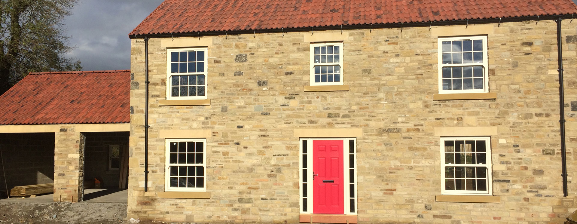 Stone house with a red composite front door and white uPVC windows
