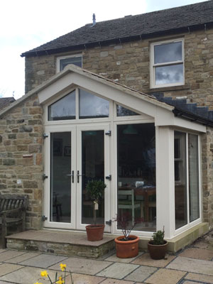White uPVC sunroom with French doors on a stone cottage